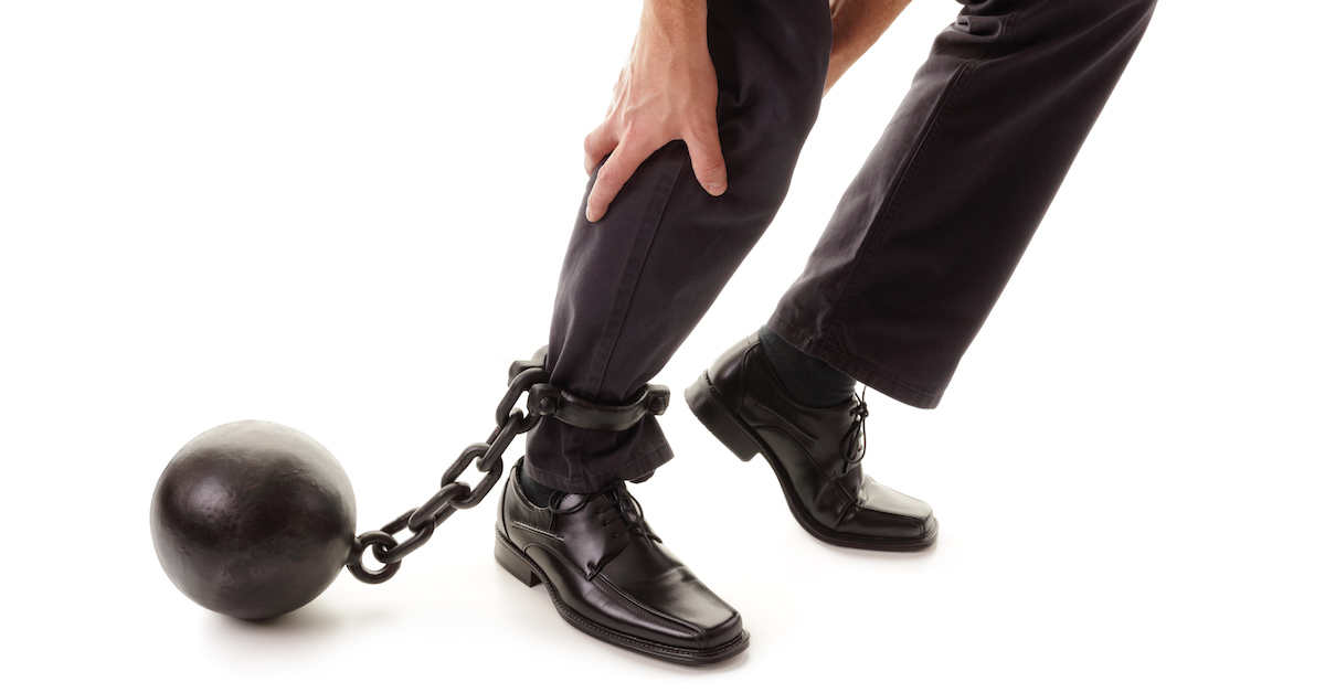 Ball and chain holding businessman back from sales